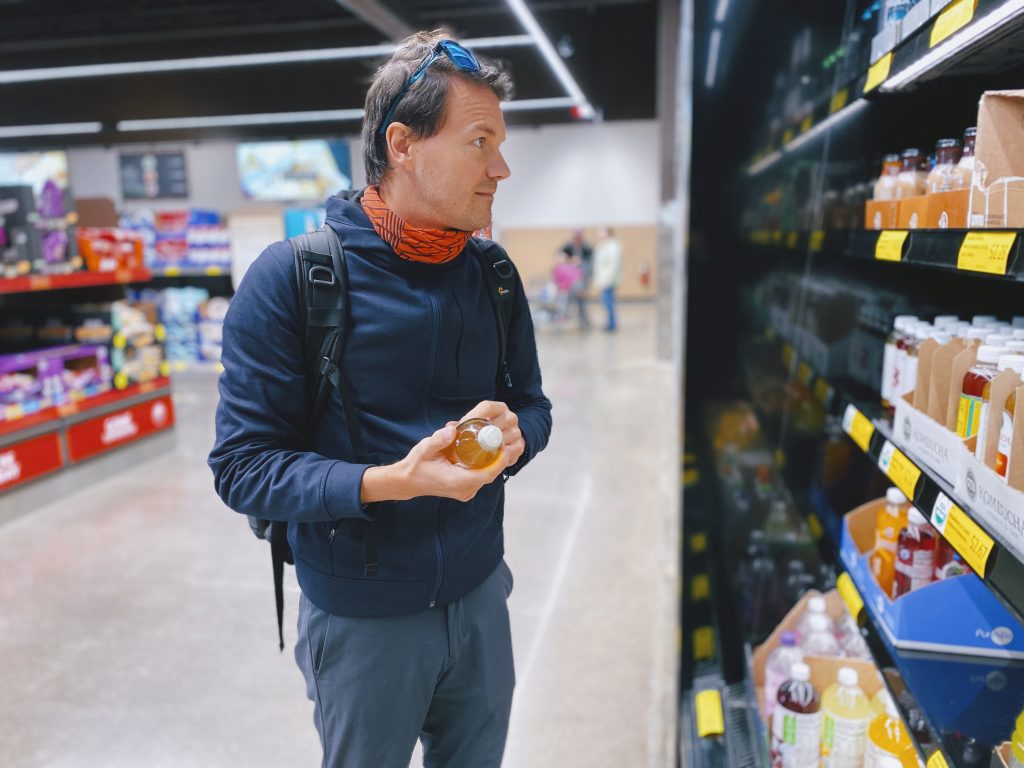 Man standing at a supermarket isle, reading nutrition labels and choosing food carefully